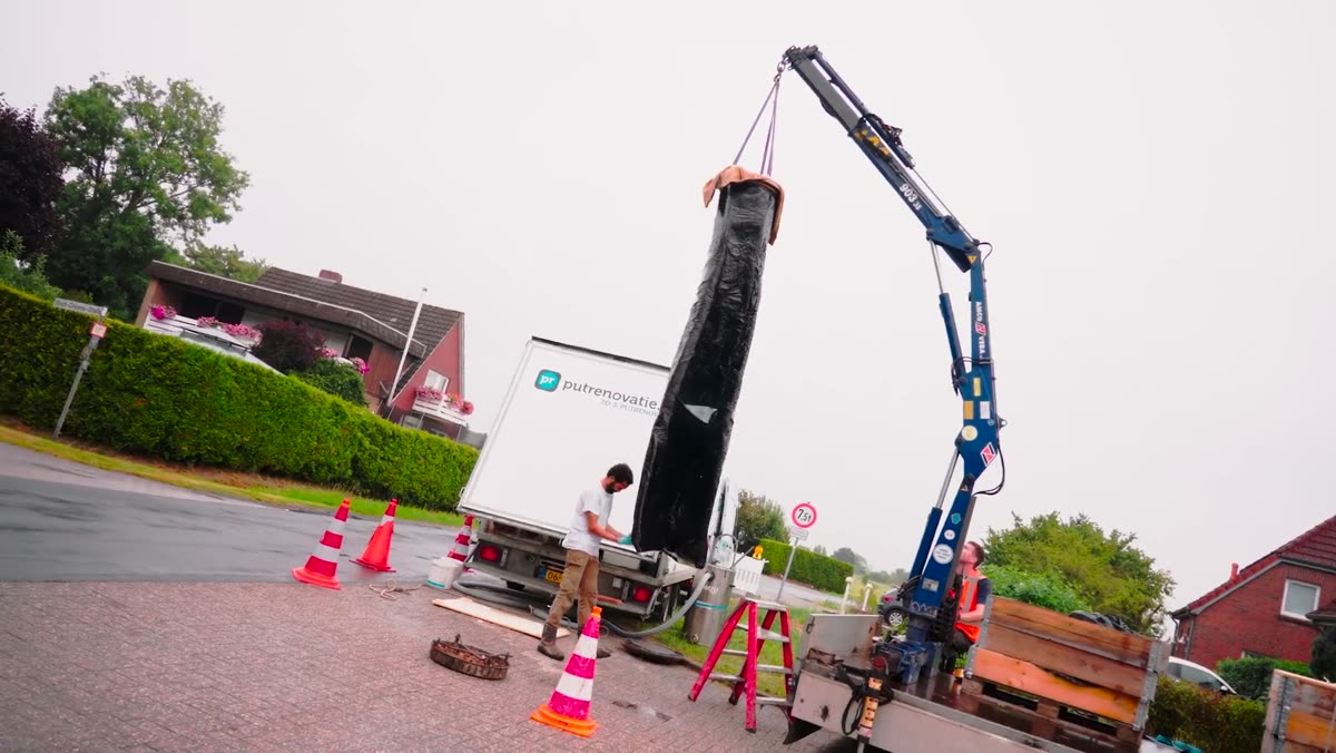 Kraan laat de liner in een put zakken in een woonwijk