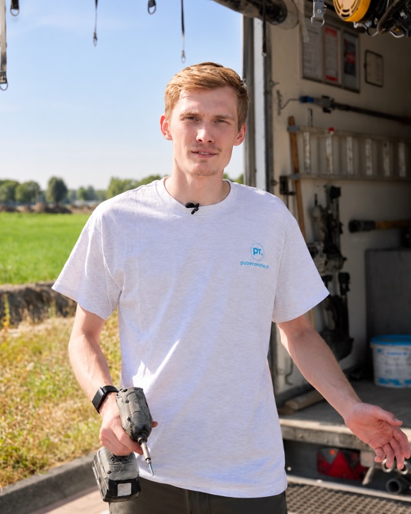 Collega van Putrenovatie met een boormachine bij de bedrijfsbus