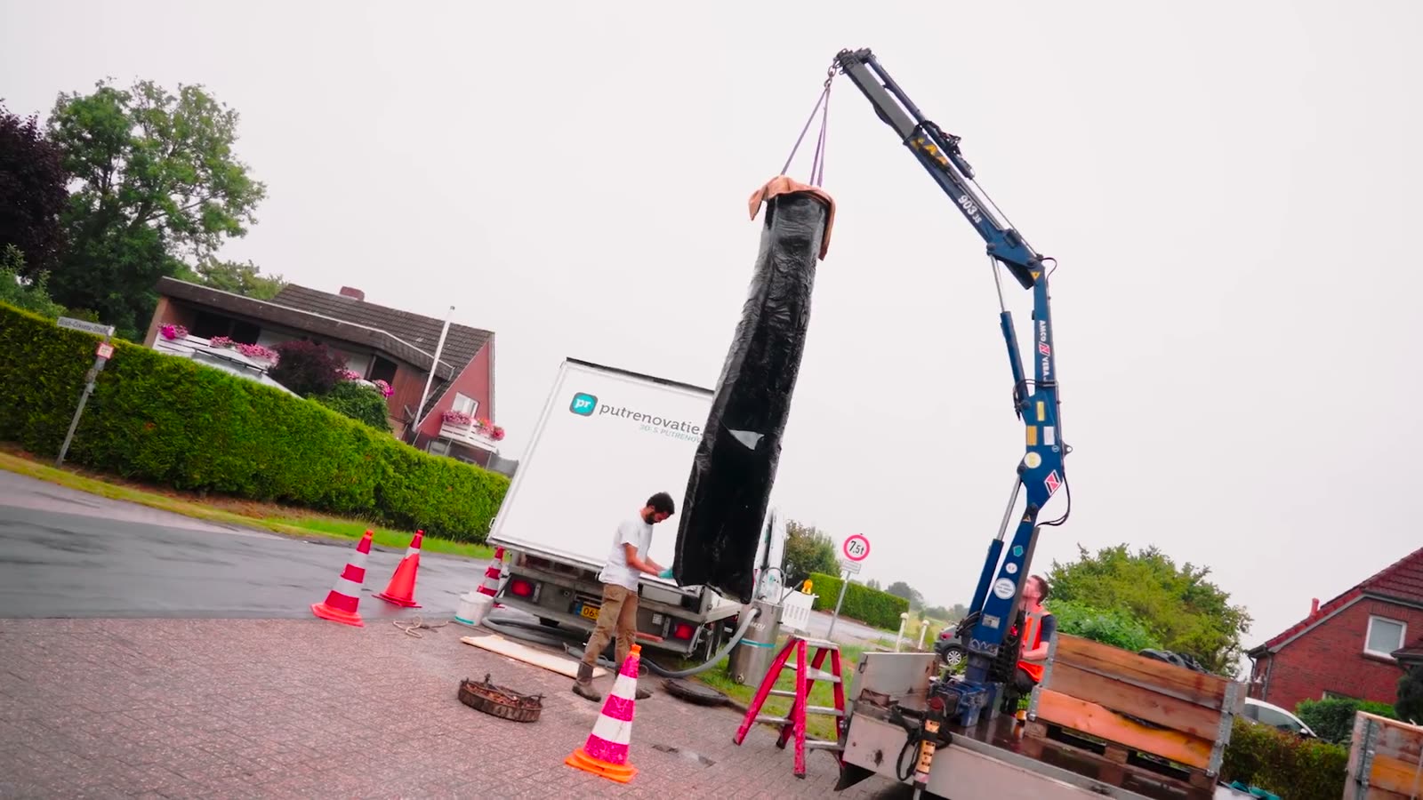 Putrenovatie aan het werk met een kraan bij een put in een woonwijk